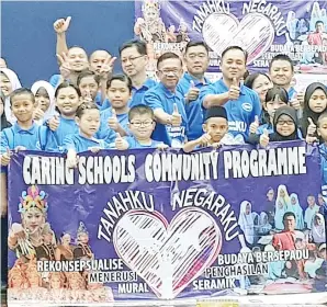  ??  ?? TAJUL (depan, kanan) bersama sepanduk ‘Caring School Community Programme’.