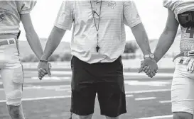  ?? Juan Figueroa/Dallas Morning News ?? Borden County High School football coach Trey Richey holds hands with players as they pray after practice in 2020 in Gail.