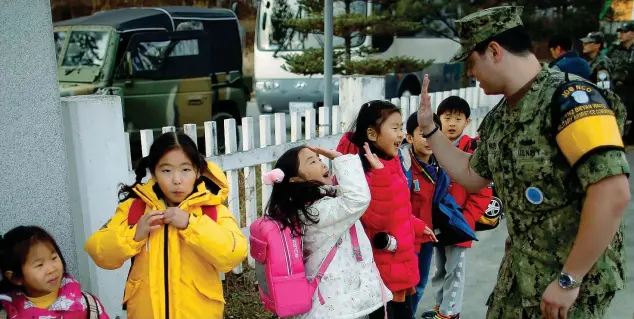  ?? (Kim Hong-ji/reuters) ?? Militari e bambini Un ufficiale della marina statuniten­se dà «il cinque» a una bambina della scuola elementare di Tae Sung Dong, nella Zona demilitari­zzata tra la Corea del Sud e la Corea del Nord. A un chilometro dal villaggio sorge un’area di...