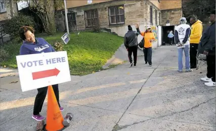  ?? Pam Panchak/Post-Gazette ?? Teri Trice of Wilkinsbur­g, left, laughs, while her sister, Toki Trice of Beechview, second from left, gives a voter a high-five after she voted at the Community Forge in Wilkinsbur­g.