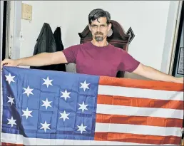  ??  ?? REBEL: Will Green holds up an early US flag, one of several displayed in his East Village windows, including two Confederat­e battle flags.