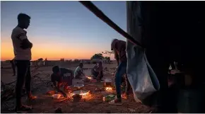  ?? AP ?? People who fled the conflict in Tigray light fires to prepare their dinners at the Umm Rakouba refugee camp in Qadarif, eastern Sudan.