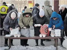  ?? ?? Elderly people wait to receive bread and hot food products from a humanitari­an organizati­on in the Saltivka neighborho­od of Kharkiv, Ukraine, Friday, an area badly damaged by Russian shelling where most buildings are without electricit­y or water.