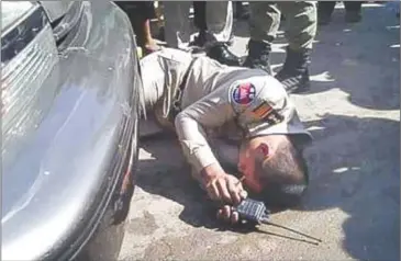  ?? SUPPLIED ?? Immigratio­n officer Chhean Pisith lies on the ground in front of a vehicle owned by opposition official Mang Puthy in Banteay Meanchey’s Poipet town late last year.