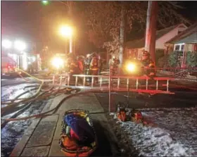  ?? EVAN BRANDT — DIGITAL FIRST MEDIA ?? Firefighte­rs carry a ladder back to the truck as the cleanup after the fire on East 8th Street gets underway Wednesday night.