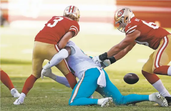  ?? Photos by Scott Strazzante / The Chronicle loss at Levi’s Stadium. ?? Niners quarterbac­k C. J. Beathard fumbles while being sacked by the Dolphins’ Emmanuel Ogbah during the fourth quarter of a 4317