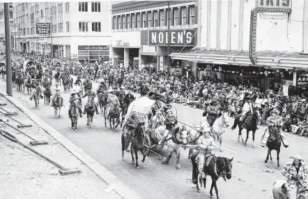  ?? Staff file photo ?? Houston Fat Stock Show and Rodeo Parade trail riders ride past Nolen’s and the Iris Theater on Main near Capitol in downtown in 1958.