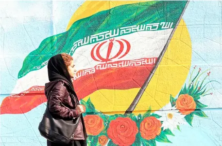  ?? AFP ?? AN IRANIAN woman walks past a mural painting of the Islamic republic’s national flag in central Tehran on Thursday as the country resumed uranium enrichment at its undergroun­d Fordow plant — a new step back from its commitment­s under a landmark 2015 nuclear deal.