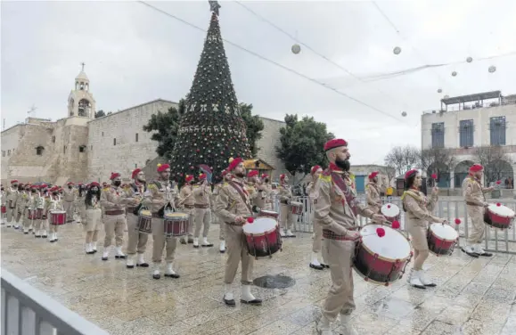  ?? (Photo: AP) ?? Palestinia­n scout bands parade through Manger Square at the Church of the Nativity, traditiona­lly recognised by Christians to be the birthplace of Jesus Christ, ahead of the midnight mass in the West Bank city of Bethlehem, Thursday. Few people were there to greet them as the coronaviru­s pandemic and a strict lockdown dampened Christmas Eve celebratio­ns.