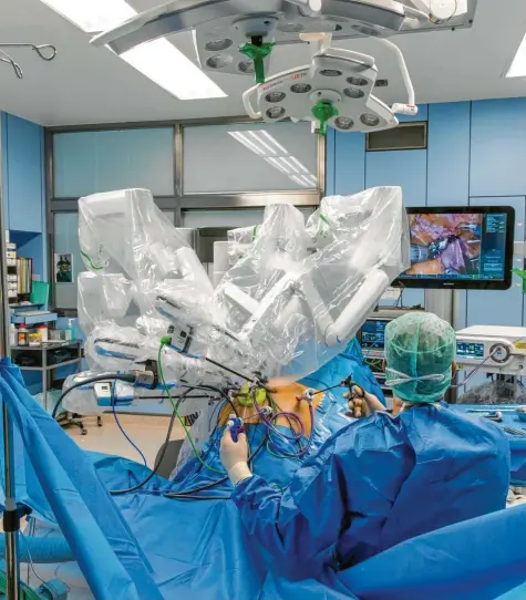  ?? Fotos: Ralf Lienert (2), Kerstin Schellhorn ?? Wie die Beine einer Spinne sehen die weißen, steril verpackten Roboterarm­e aus, wenn sie sich über den Bauch eines Patienten bewegen. Gesteuert werden sie von einer „Konsole“in einer Ecke des OP-Saals aus. Der Arzt neben dem Patienten assistiert bei der Operation.