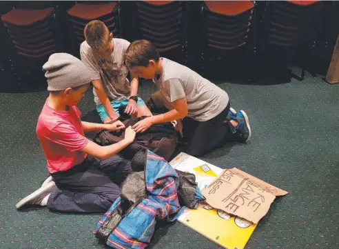  ??  ?? EYE OPENING: Sidney Whipp, Shannon Galbraith and Archie Rudolphy of St Augustine’s College check out a homeless person's bag.