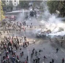  ??  ?? Un cañón de agua de la policía rocía a manifestan­tes frente al palacio presidenci­al en Chile.