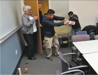  ?? Carlos Avila Gonzalez / The Chronicle ?? At a UC Berkeley drill to teach survival during a shooting, Marsha Jaeger (left) and Juan Manriquez (right) defend themselves against the gunman, played by Boun Khamnouane.