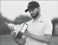  ??  ?? Kyle Stanley looks at the trophy after winning the Quicken Loans National golf tournament on Sunday in Potomac, Md.