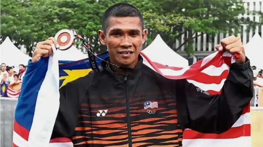  ??  ?? Impressive
feat: Malaysia’s Muhaizar Mohamad showing off the men’s marathon bronze medal in Putrajaya yesterday.