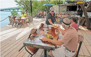  ?? ANDY NEWMAN
FLORIDA KEYS NEWS BUREAU ?? Alexeen Simms serves a meal to a couple at the Hungry Tarpon Restaurant in Islamorada, Fla., on Monday. The Florida Keys reopened to tourists Monday after being closed since March 22.