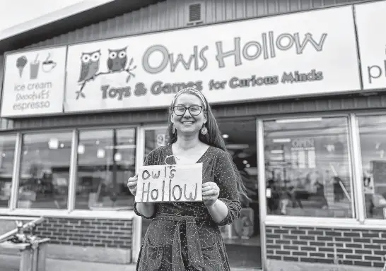  ?? THINH NGUYEN • THE GUARDIAN ?? Emily Bender, a staff member at Owl’s Hollow in Charlottet­own, holds the small wooden sign bearing the store’s name. The staff discovered the sign outside the door last year.