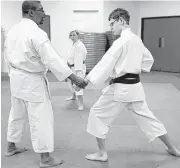  ??  ?? Griffith, right, demonstrat­es a move with his sensei, Ricardo Johns, at Dao-Ichi Shotokan Karate-Do.