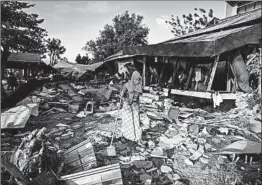  ?? MOHD RASFAN/GETTY-AFP ?? A survivor clears debris Monday from her damaged home in hard-hit Palu, Indonesia.