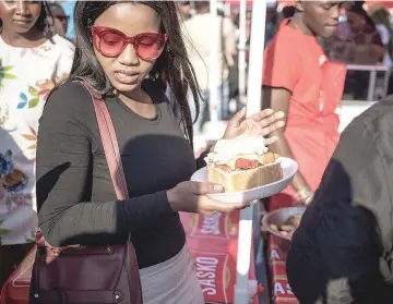  ??  ?? A South African woman purchases a ‘Kota’ sandwich during the Kota Festival.
