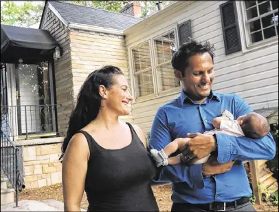  ?? CURTIS COMPTON / CCOMPTON@AJC.COM ?? New homeowners Melissa and Atandra Burman stand outside the family home with their newborn daughter, Ariyana, recently. The Burmans moved from San Francisco, the poster child for real estate insanity. “We are paying less here than what we paid for a studio apartment in San Francisco,” Melissa Burman said.