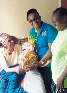  ??  ?? Centenaria­n Eunis Pryce accepts a gift basket from chairman of the St Ann Parish Council’s Civic Affairs Committee Genevor Gordon-Bailey, while her daughter, Valda Pryce, looks on.
