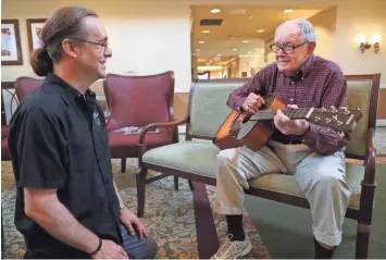  ?? jsonline.com/news. MICHAEL SEARS / MILWAUKEE JOURNAL SENTINEL ?? Patrick Nettesheim (left), founder of Guitars for Vets, presents a new, donated guitar Friday to Navy veteran David McMahon, 92, at Newcastle Place in Mequon. McMahon was excited to play the guitar again. More photos and video at