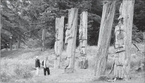  ?? — PNG FILES ?? A couple stand next to ancient Haida poles on Anthony Island in Gwaii Haanas National Park Reserve.