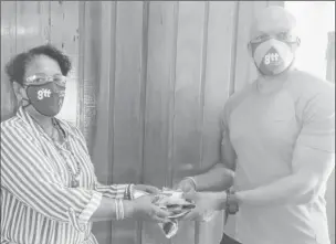  ??  ?? Orson Ferguson (right) handing over the masks to Debra King (GTT photo)