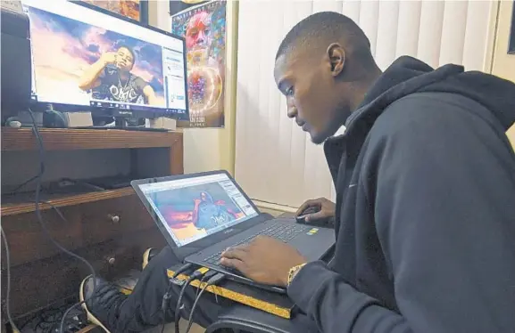  ?? KENNETH K. LAM/BALTIMORE SUN PHOTOS ?? Trevon Jackson works on a poster of a recent homicide victim. Jackson has a following on Instagram for memorial posters of loved ones with angel wings that he creates and posts.