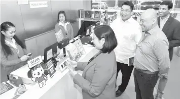  ??  ?? National Book Store Managing Director Xandra Ramos-Padilla tries the GCash scan to pay feature while (from L-R): National Bookstore VP and CFO Adrian Ramos, Globe President and CEO Ernest Cu, and Mynt President and CEO Anthony Thomas look on.