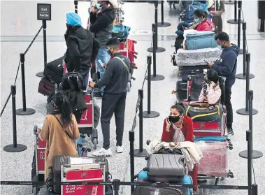  ?? RICHARD LAUTENS TORONTO STAR ?? Passengers wait in line for hotel shuttles after arriving at Pearson airport on Monday, as new federal health rules requiring COVID-19 tests and mandatory hotel quarantine­s for internatio­nal travellers came into effect.