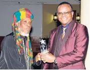  ??  ?? Mutabaruka (left) is presented with the Bush Doctor Award, by Copeland Forbes at the Peter Tosh memorial event last week.