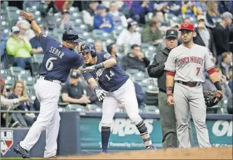  ?? [MORRY GASH/THE ASSOCIATED PRESS] ?? Milwaukee third-base coach Ed Sedar congratula­tes Hernan Perez for an RBI triple in the second inning Tuesday night in Milwaukee. Cincinnati third baseman Eugenio Suarez stands by.