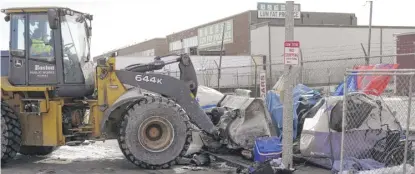  ?? CHARLES KRUPA/AP ?? A front end loader scoops up tents, furniture and other items as a homeless encampment is cleared Wednesday in Boston.