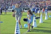  ?? / Spencer Lahr ?? Johnson Elementary Principal Tanya Welchel runs along with student Khloe Parton as the balloon slips out from between her knees as she races to get through the megaphones to pop the balloon.