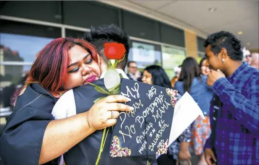  ?? Michael M. Santiago/Post-Gazette ?? Andrea Peraza, left, hugs her brother Oscar Peraza, center, after the conclusion of the Brashear High School graduation ceremony June 9 at Petersen Events Center in Oakland. Andrea Peraza is one of many individual­s who came to the U.S. as an unaccompan­ied minor seeking and being granted asylum in search for a better life from the violence in El Salvador. ... ‘I can do this. This is a path that is available to me.’