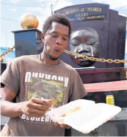  ??  ?? Theo Mullings makes light work of breakfast in front of the Secret Garden monument in downtown Kingston yesterday. Mullings was one of hundreds of homeless persons who were served breakfast during the launch of a special feeding programme in the parking lot of the Kingston and St Andrew Municipal Corporatio­n on Church Street in Kingston.