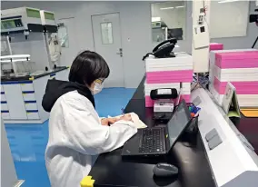  ??  ?? A staff working in the Guangzhou Bioseal Biotech Laboratory, founded by Johnson & Johnson, wears a face mask while working.