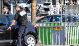  ?? THIBAULT CAMUS / AP ?? Police officers examine the attacker’s car (center rear) after a man rammed into a police convoy on the Champs Elysees Avenue in Paris on Monday. France’s interior minister says the threat of terrorism remains very high in the country.
