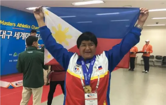  ?? Contribute­d photo ?? LOUD AND PROUD. Baguio super senior athlete Erlinda Lavandia carries the Philippine flag after winning the gold medal in the javelin throw event in the 2017 World Masters Athletics Indoor Championsh­ips recently at the Blue Arc stadium in Daegu, South Korea with a heave of 30.58 meters.