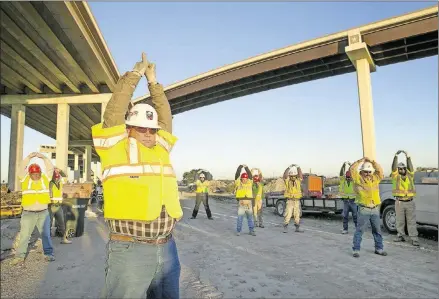  ?? JAY JANNER / AMERICAN-STATESMAN PHOTOS ?? General Superinten­dent Monte Cook and other workers with McCarthy Building Companies do exercises before their shift Nov. 21.