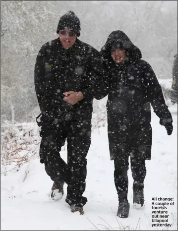  ??  ?? All change: A couple of tourists venture out near Ullapool yesterday