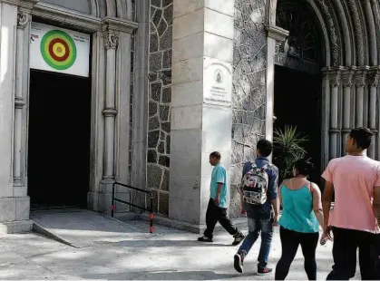  ?? Rubens Cavallari/Folhapress ?? Pedestres observam o painel colorido instalado sobre uma das entradas da Igreja de Nossa Senhora da Consolação (região central); padre e fiéis afirmam que cartaz, instalado há três meses, hipnotiza pombos