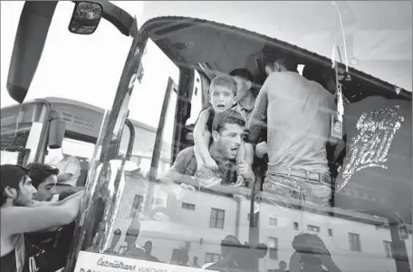  ?? Jeff J Mitchell
Getty Images ?? A BOY is carried aboard a bus in Beli Manastir, Croatia, near the Hungarian border. Buffeted by thousands of migrants, the country began sending busloads to an unwilling Hungary, which eventually allowed people to pass through but called the move...