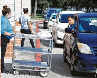  ?? Karen Warren / Staff photograph­er ?? Norma Ocotiela brings meals out on a cart as staff give food to students at Best Elementary. Food workers handed out about 1,700 cold breakfasts and 1,700 cold lunches Wednesday evening.