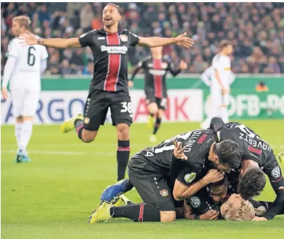  ?? FOTO:
DPA ?? Leverkusen­er Feiertraub­e im Borussia-Park: Karim Bellarabi eilt, um mit denKollege­n den Führungstr­effer zum 1:0 von Julian Brandt (am Boden liegend) gebührend zu würdigen.