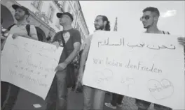  ?? KARL-JOSEF HILDENBRAN­D, THE ASSOCIATED PRESS ?? Refugees, some from Syria, and their supporters demonstrat­e with posters written with “we love peace,” right, and “they aren’t acting in my name” in Wuerzburg, Germany, Wednesday.