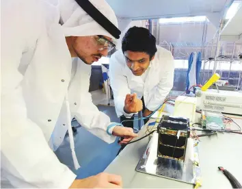  ?? Pankaj Sharma/Gulf News ?? Dr Prashanth Marpu, associate professor at Khalifa University (right) and Abdullah Al Ansari, a team member of the MYSAT 1 project work on the engineerin­g model of MYSAT 1.