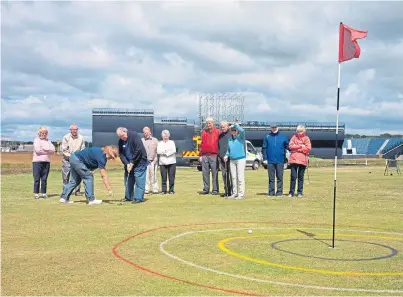  ??  ?? Members of the Carnoustie Golf Memories Group get in some putting practice in the shadow of the giant stands going up ahead of next month’s Open Championsh­ip. Picture: Newsline Media.